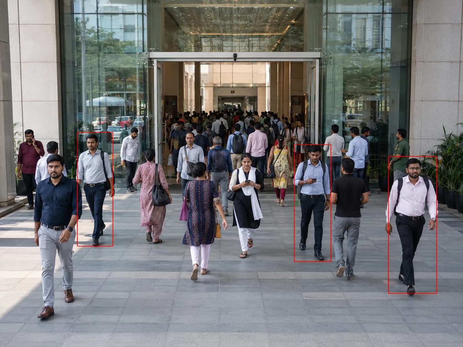 Crowd of people tracked with bounding boxes entering a building lobby for presence monitoring
