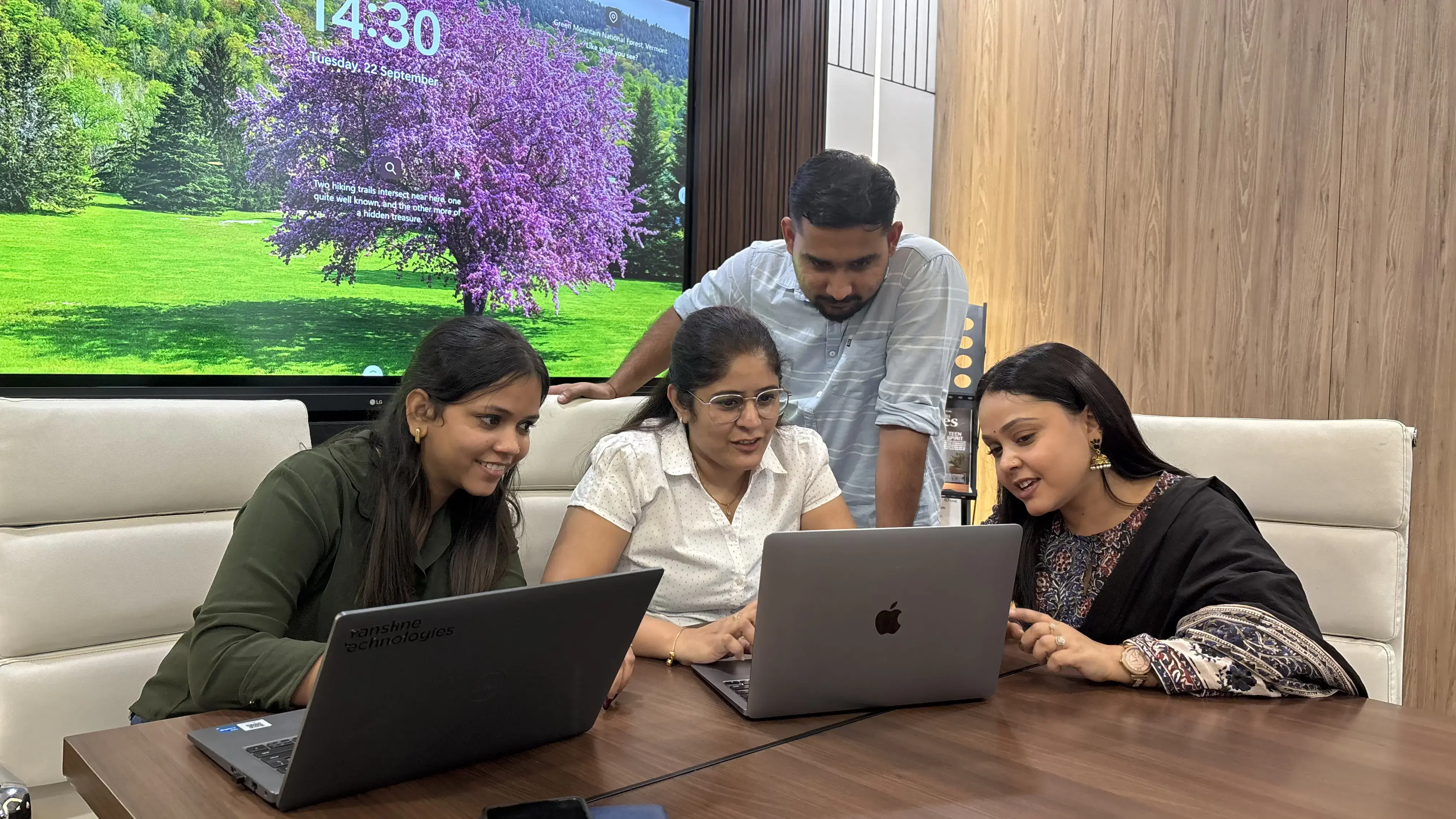 Colleagues collaborating on laptops in a meeting room