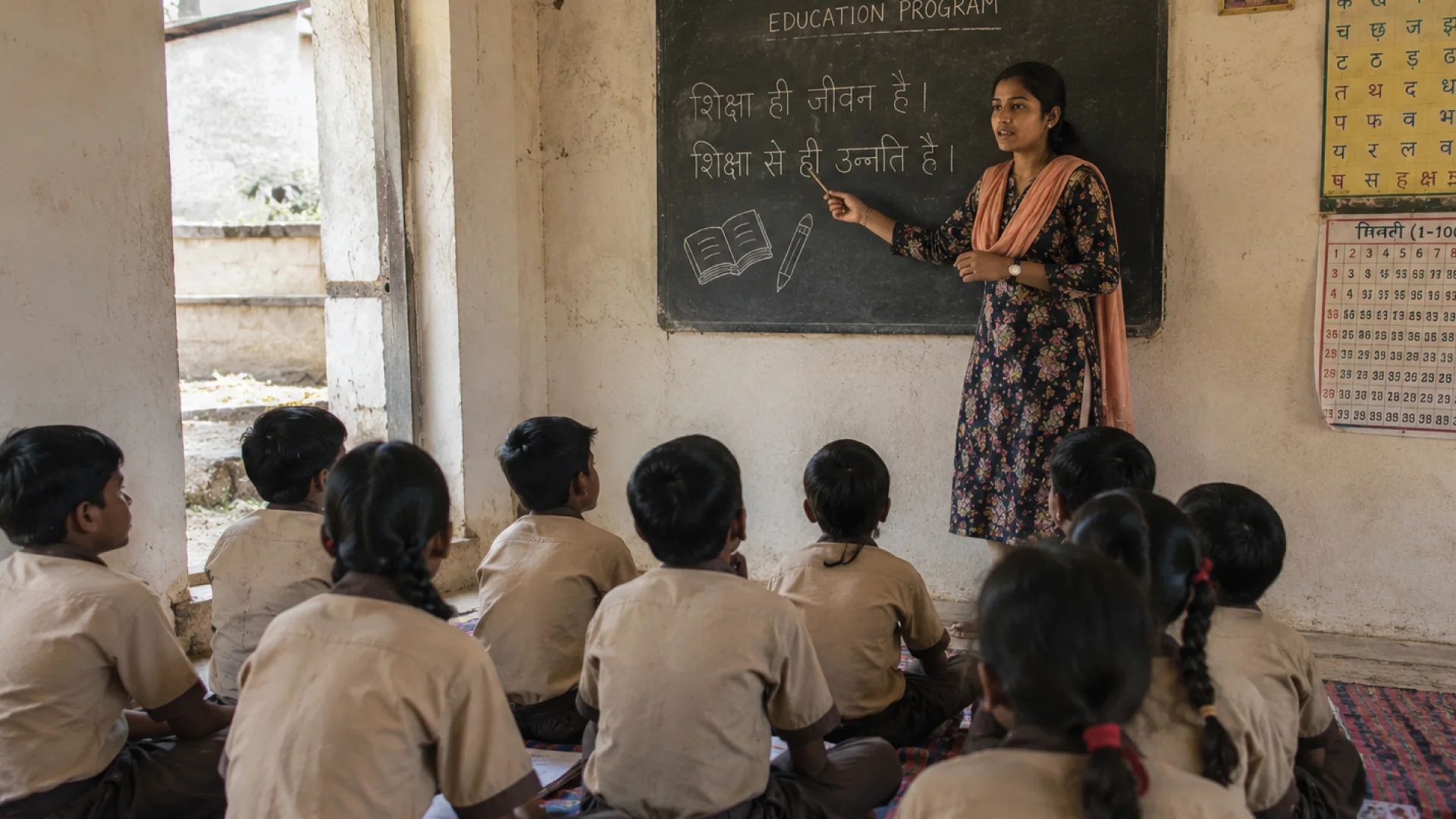 Education Programme for Village Children Teacher explaining a lesson on the blackboard to children in a village school classroom